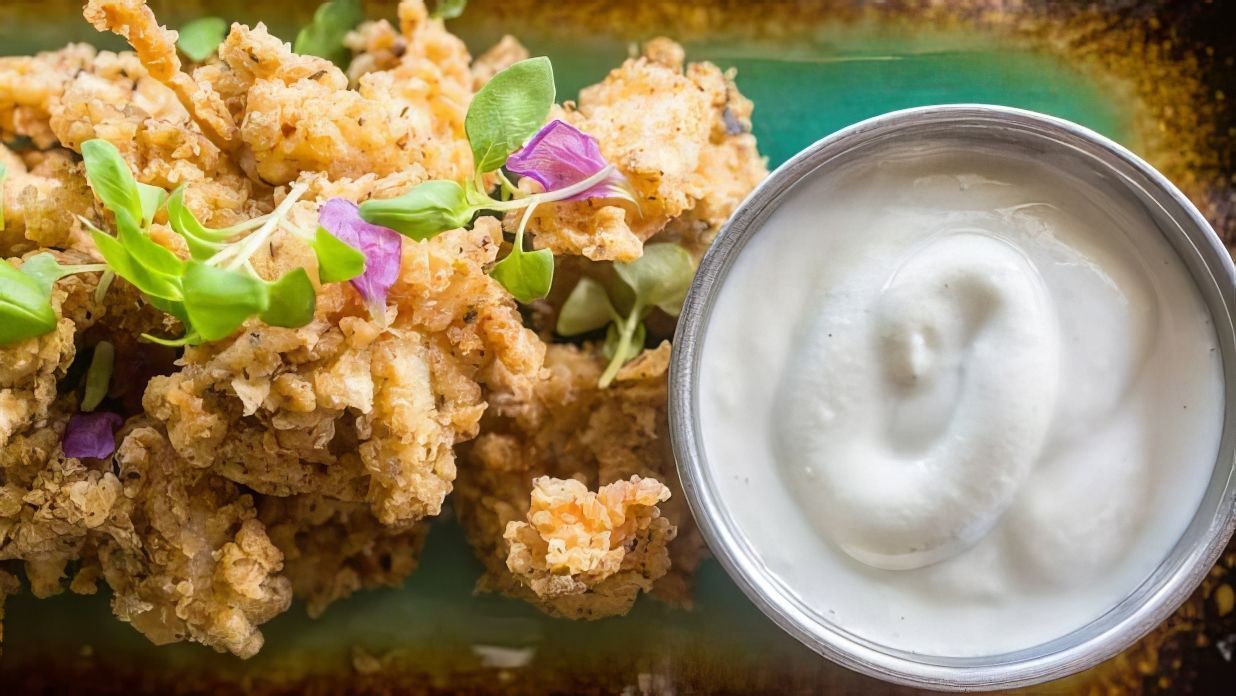 A bowl of sour cream next to a plate of food