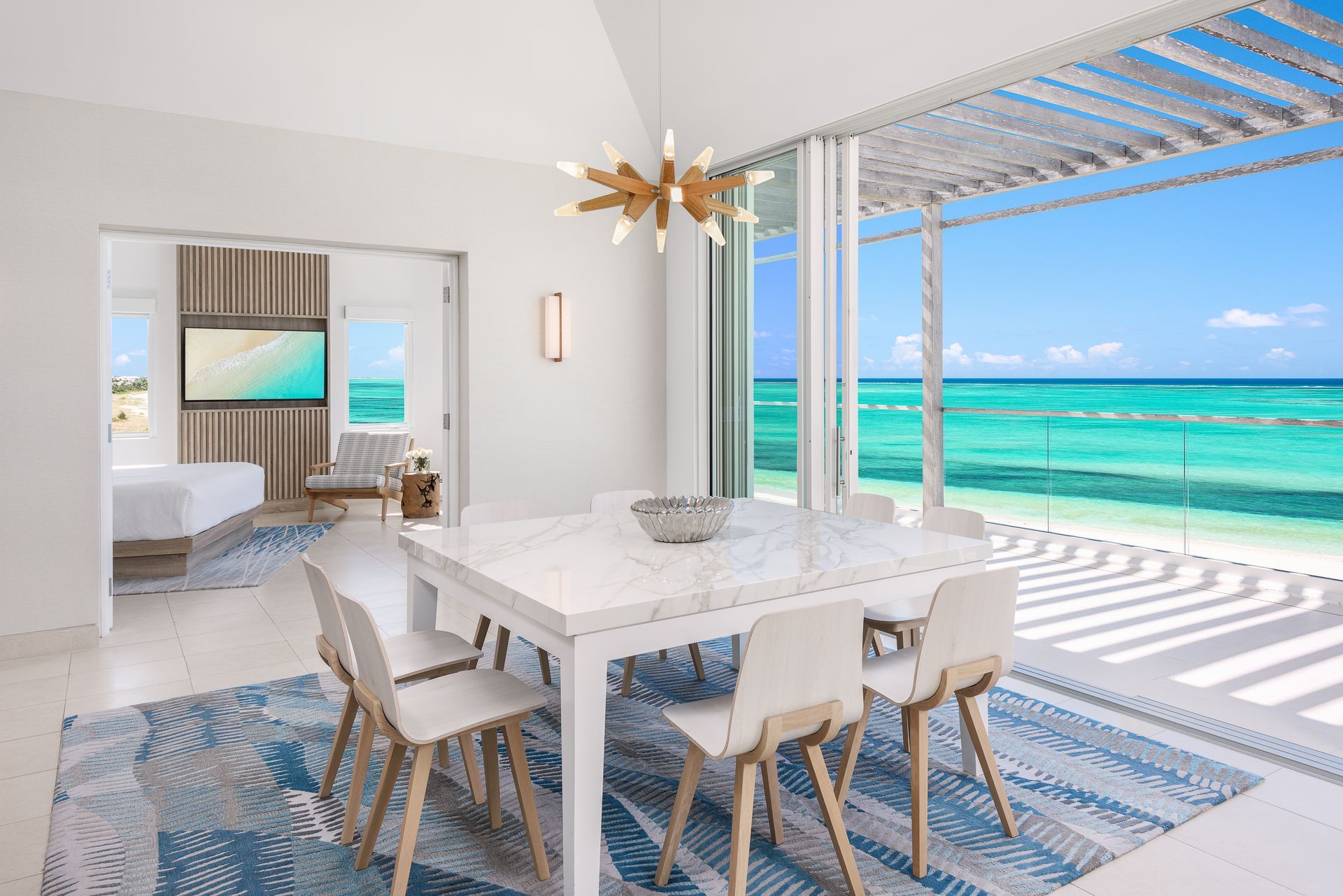 A dining room with a table and chairs and a view of the ocean