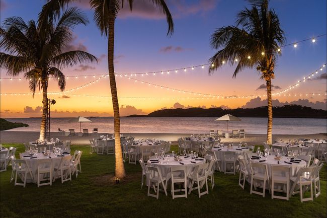 Tables and chairs set up on a beach at sunset