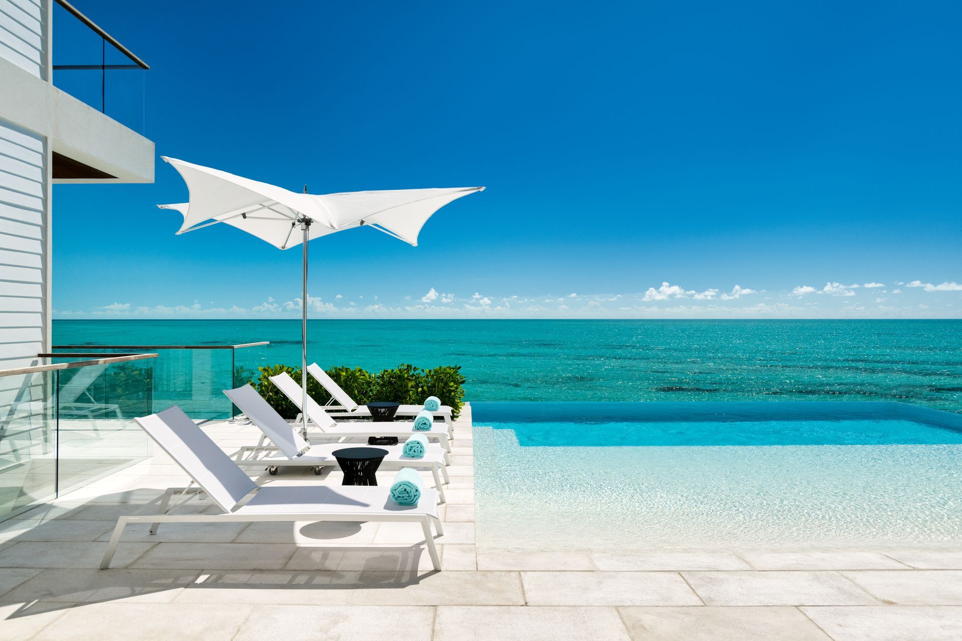 A swimming pool with chairs and umbrellas overlooking the ocean