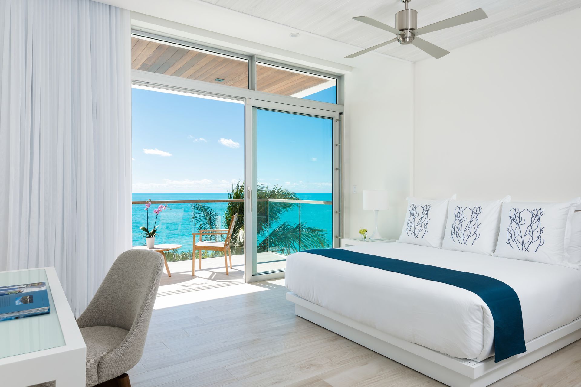 A bedroom with a large bed and a balcony overlooking the ocean