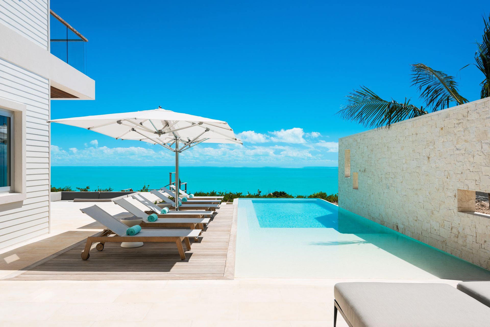 A swimming pool surrounded by chairs and umbrellas overlooking the ocean