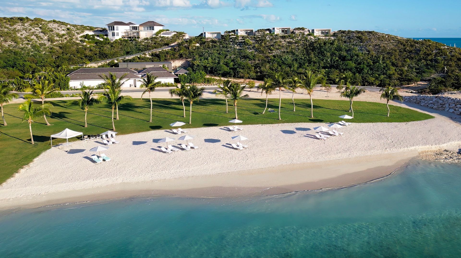 An aerial view of a beach with chairs and umbrellas