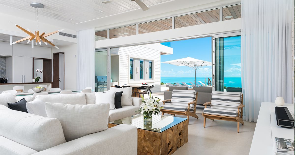 A living room with white furniture and a view of the ocean