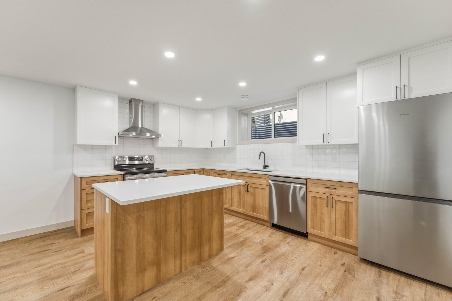 Bright modern kitchen with white cabinets, wood island, stainless steel appliances, and light wood floors