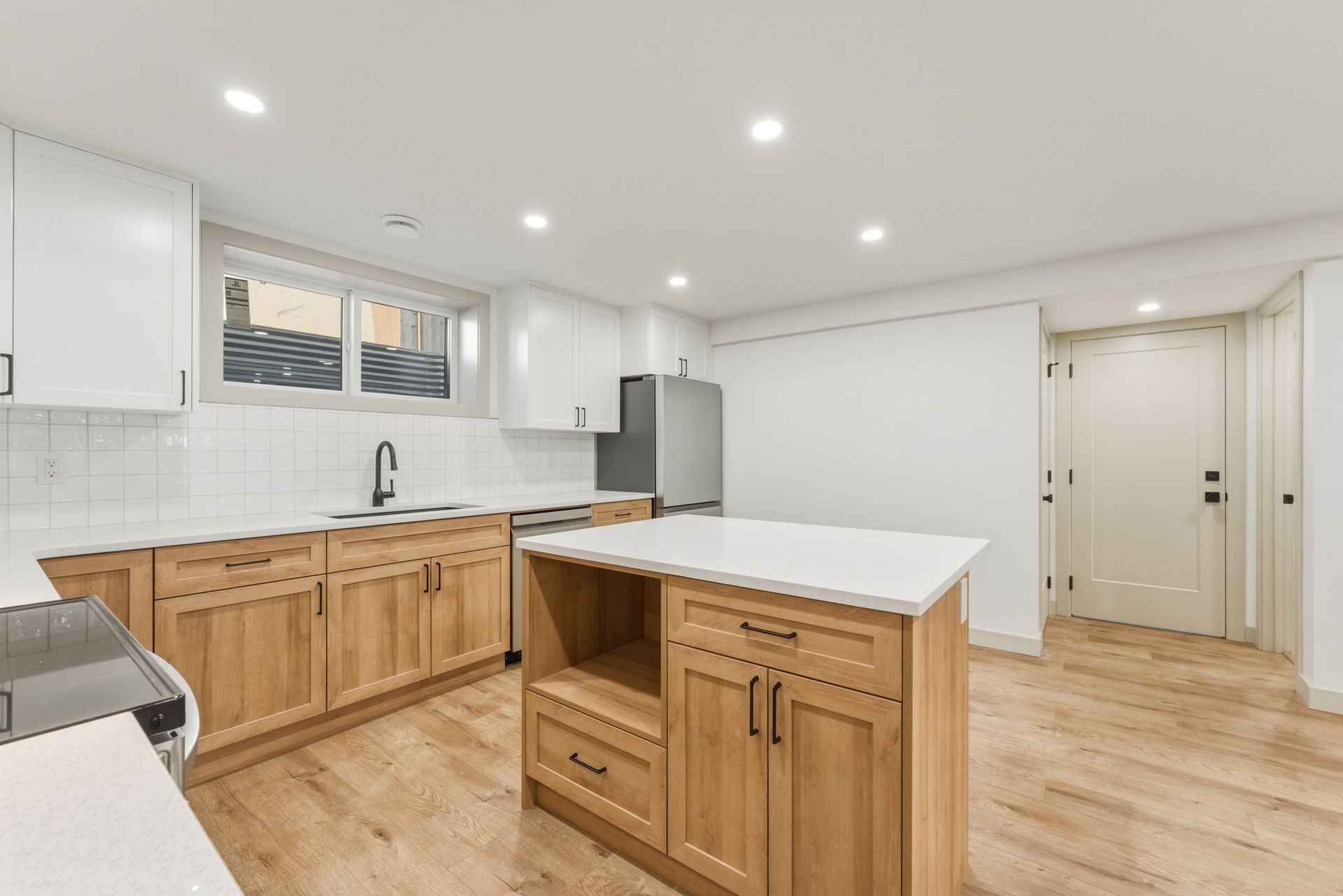 Bright modern kitchen with white cabinets, wood island, stainless appliances, and light wood floors