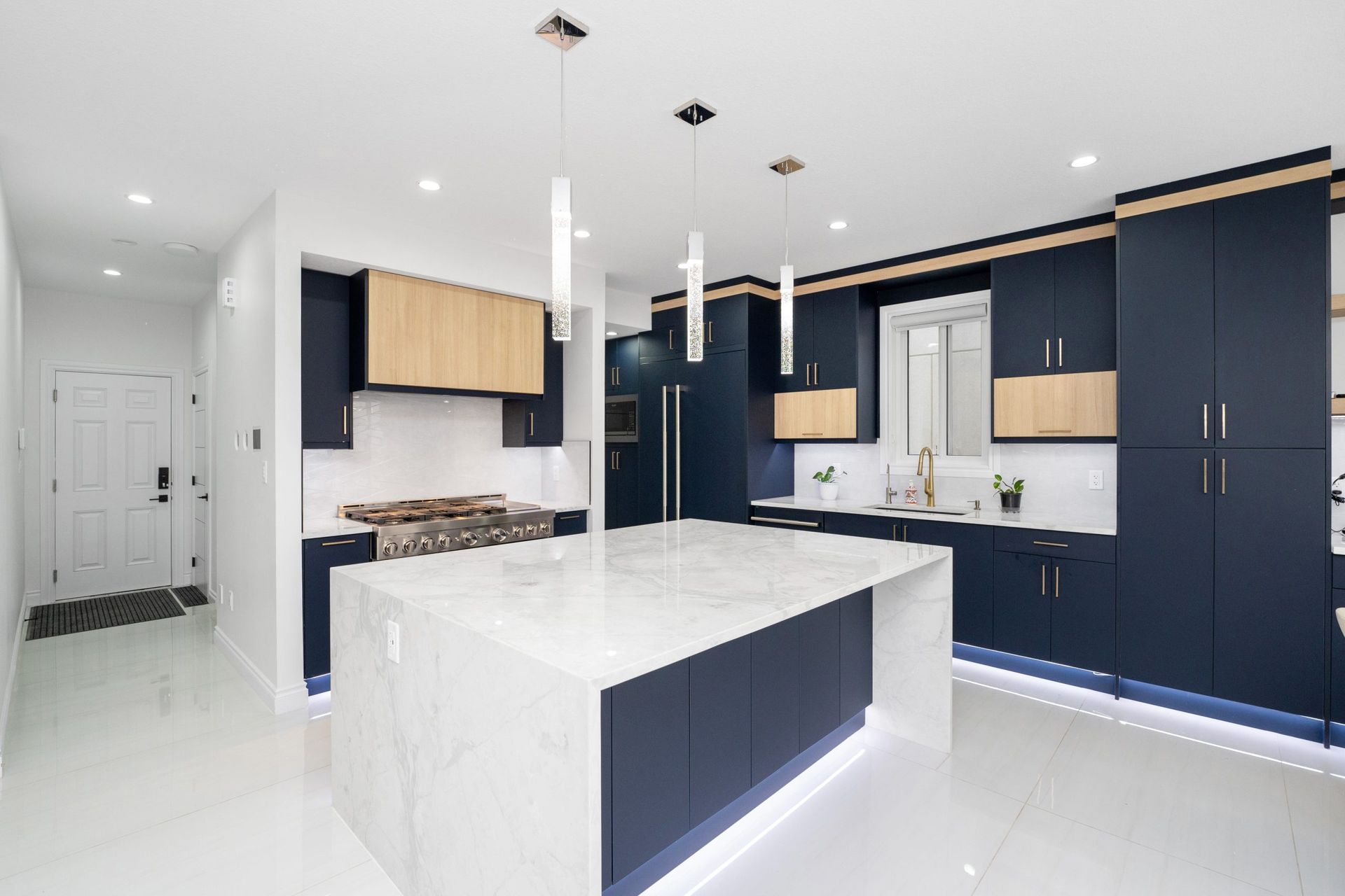 Modern white kitchen with navy cabinets, large island, and bright minimalist design