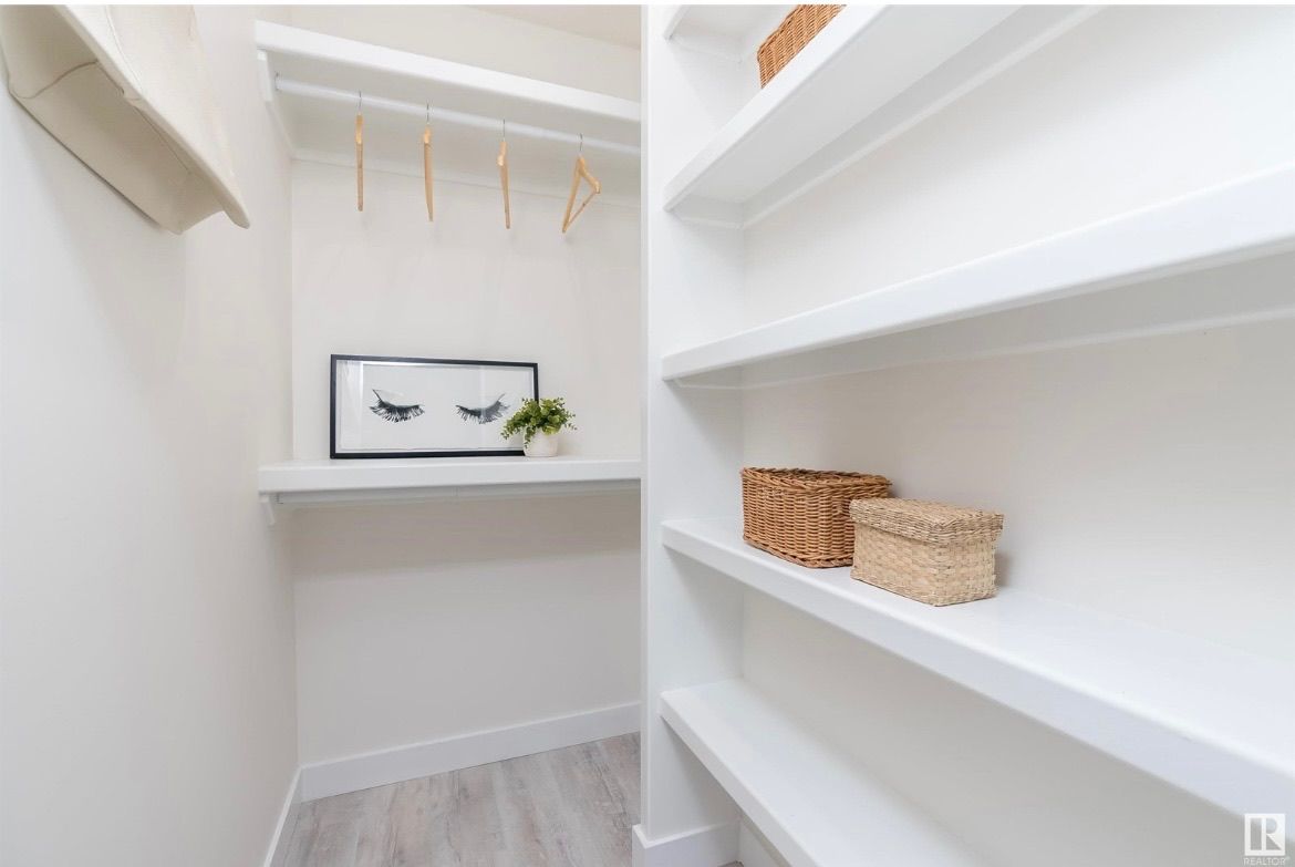 Bright white walk-in closet with shelves, hanging rods, woven baskets, and a small plant on a shelf