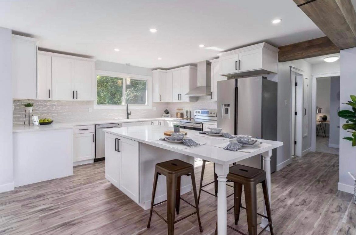 Bright modern kitchen with white cabinets, island, stools, and stainless steel refrigerator