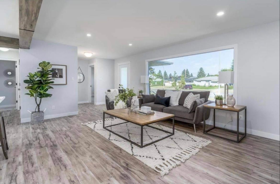 Bright modern living room with gray sofa, coffee table, large window, and wood-look floors