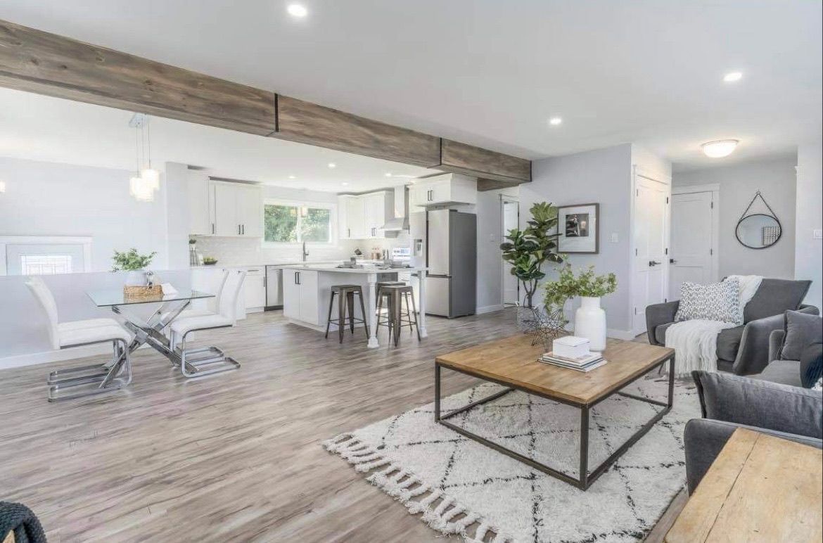 Bright open-concept living room with white kitchen, wood floors, gray sofa, and coffee table.
