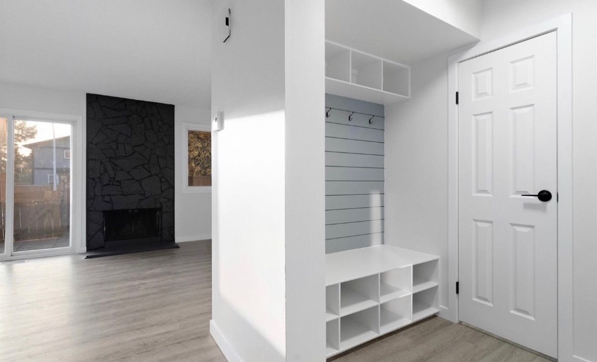 Bright entryway with white closet, shoe cubbies, and a view into a room with a fireplace and sliding doors