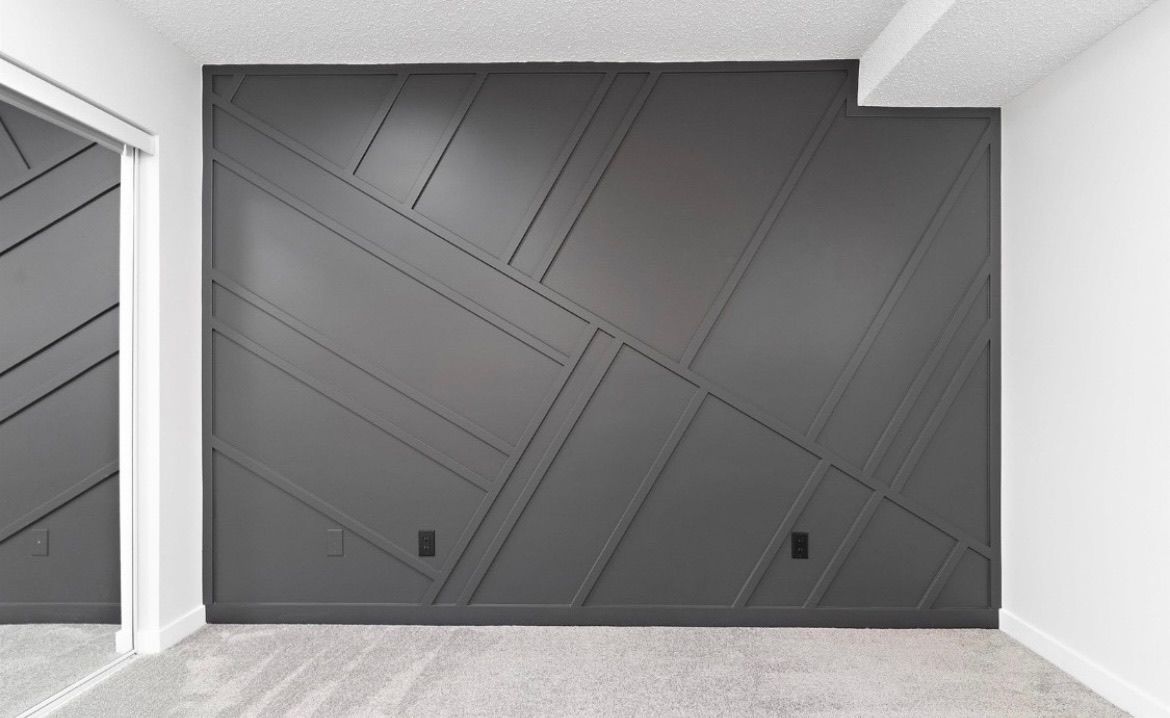 Modern gray accent wall with diagonal lines in a bright, empty interior room.