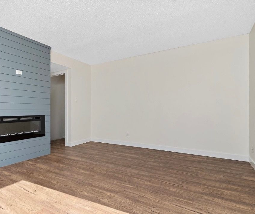 Empty living room with wood floors, white walls, and a gray fireplace accent wall