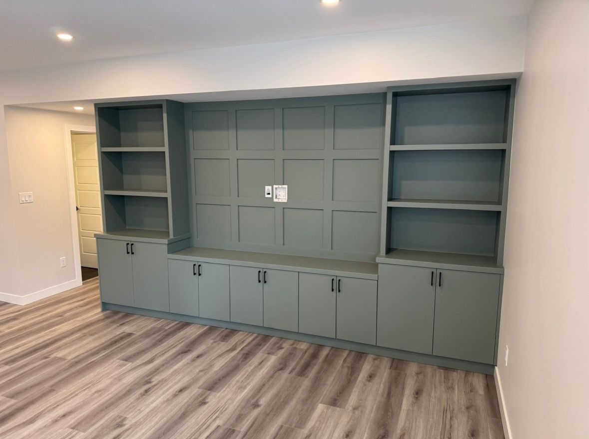 Built-in gray wall cabinet with shelves and closed storage in a room with wood flooring