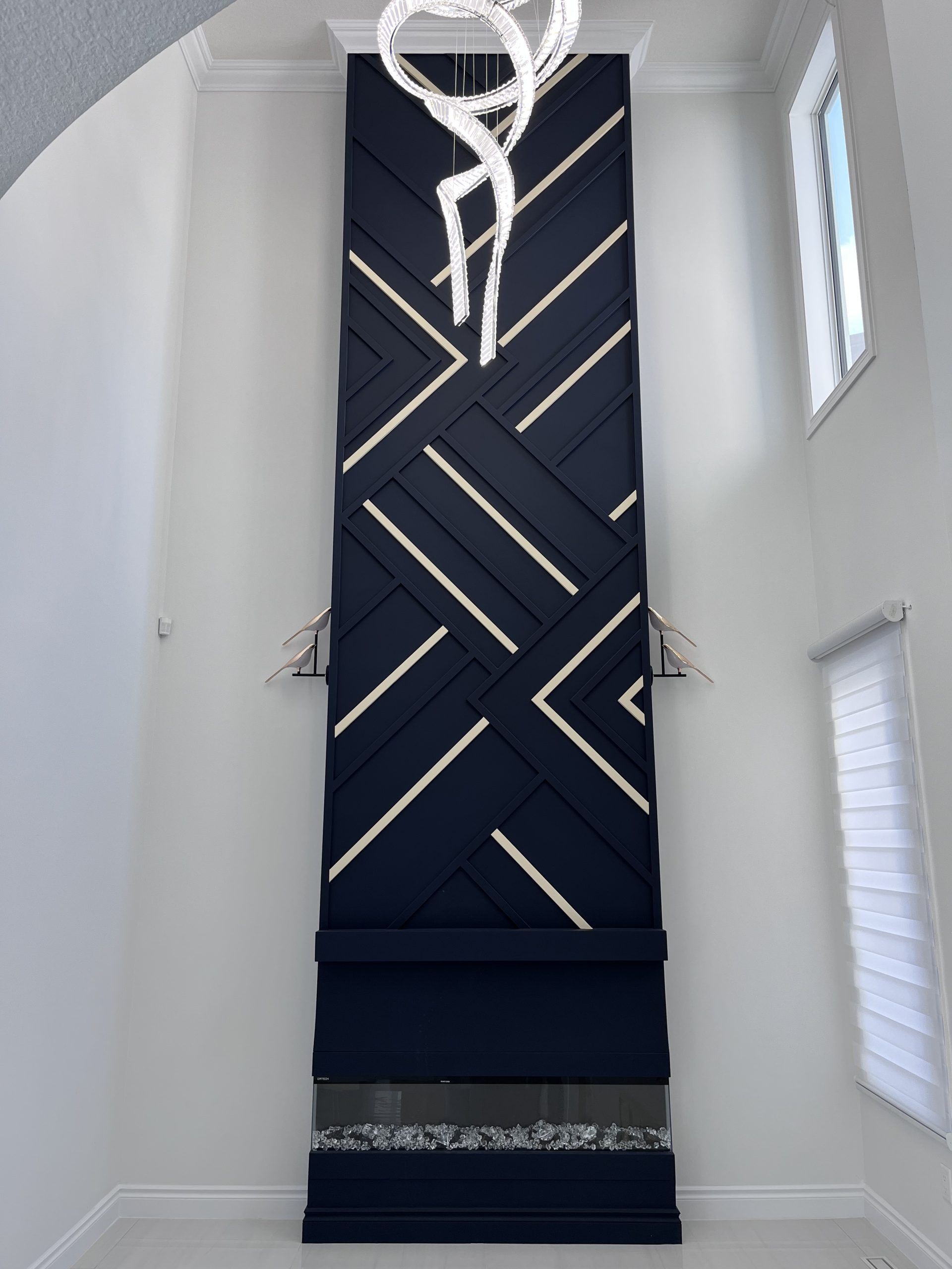 Navy geometric staircase runner in a bright white hallway with a chandelier above