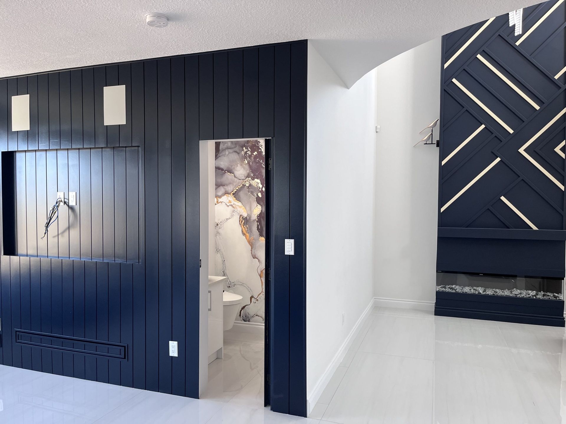 Modern room with dark navy wall panels, white floor, and a geometric accent wall in the background