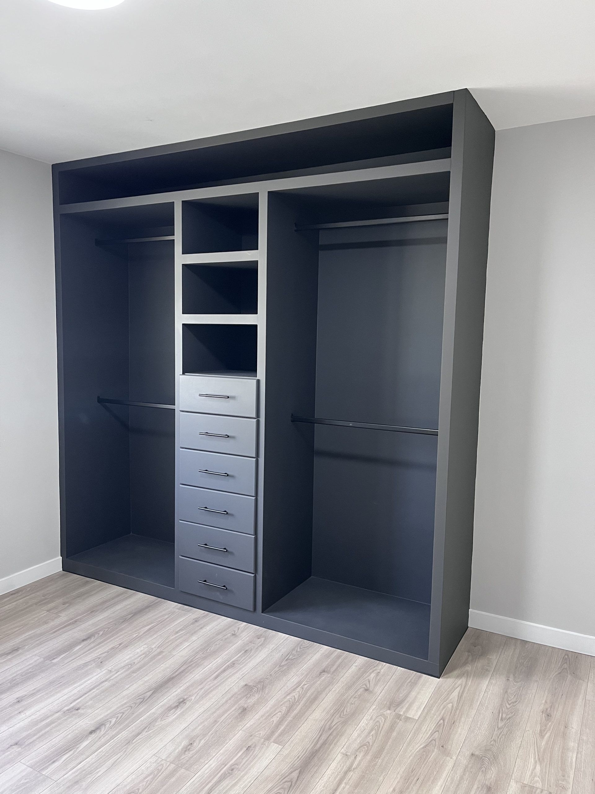 Large gray open closet with shelves, drawers, and hanging space in a carpeted room