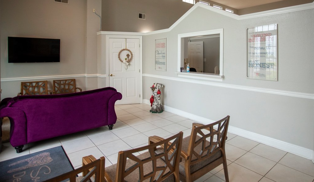 A living room with a purple couch , chairs , and a television.
