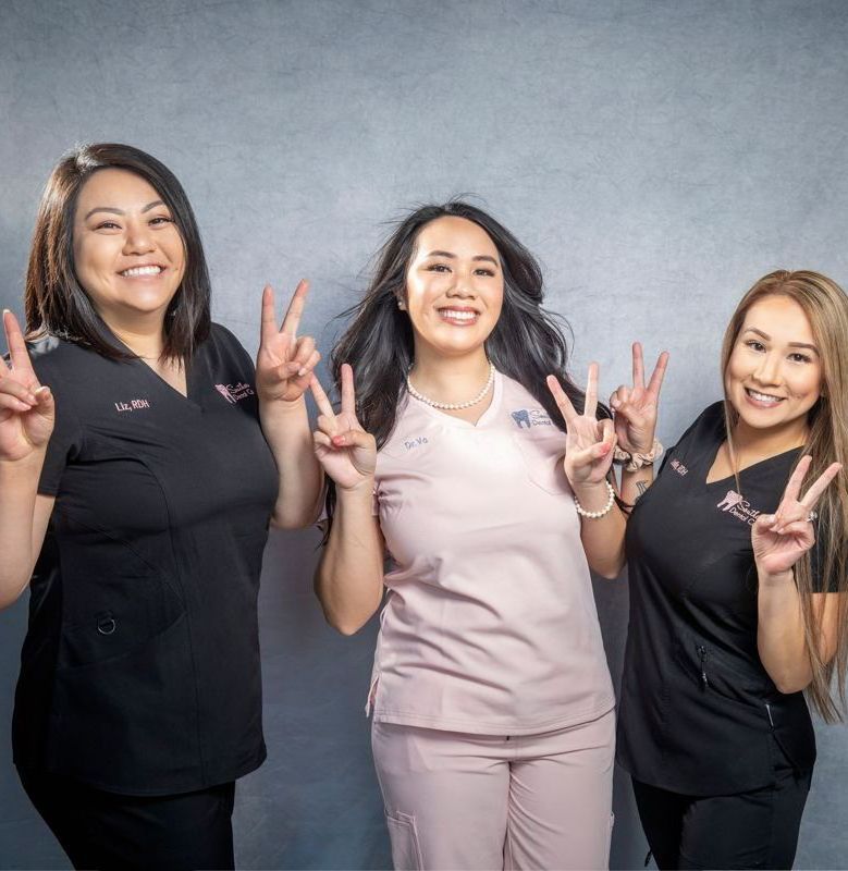 Happy dental office staff holding up the peace sign | Holistic dentist in Marrero LA