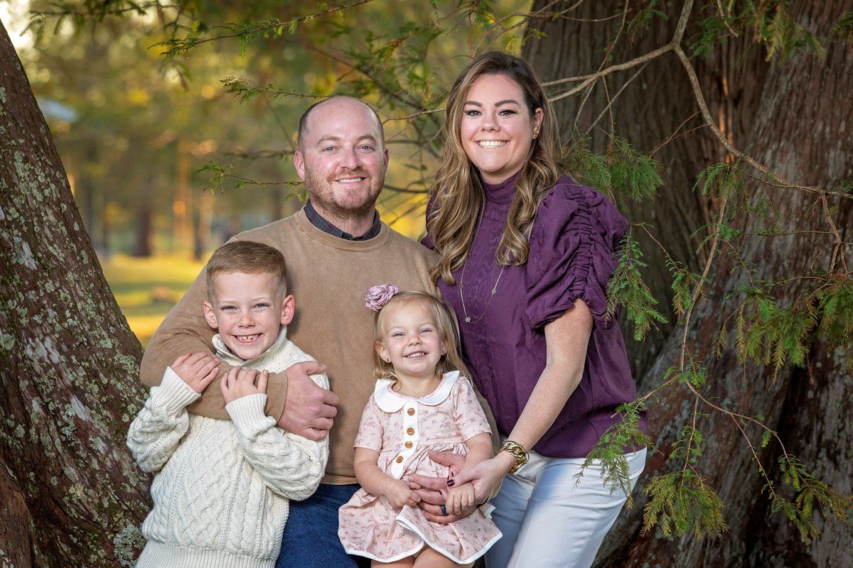 A family is posing for a picture in front of a tree.