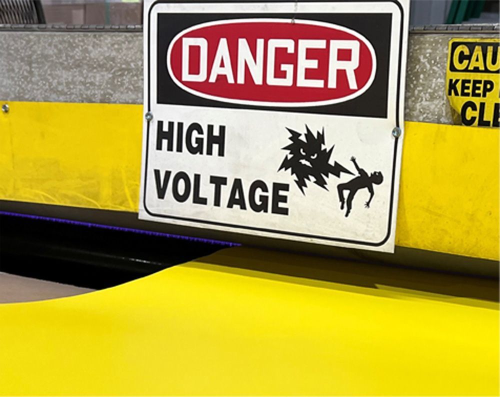 Danger high voltage sign with graphic of a person being electrocuted. Yellow and gray background.