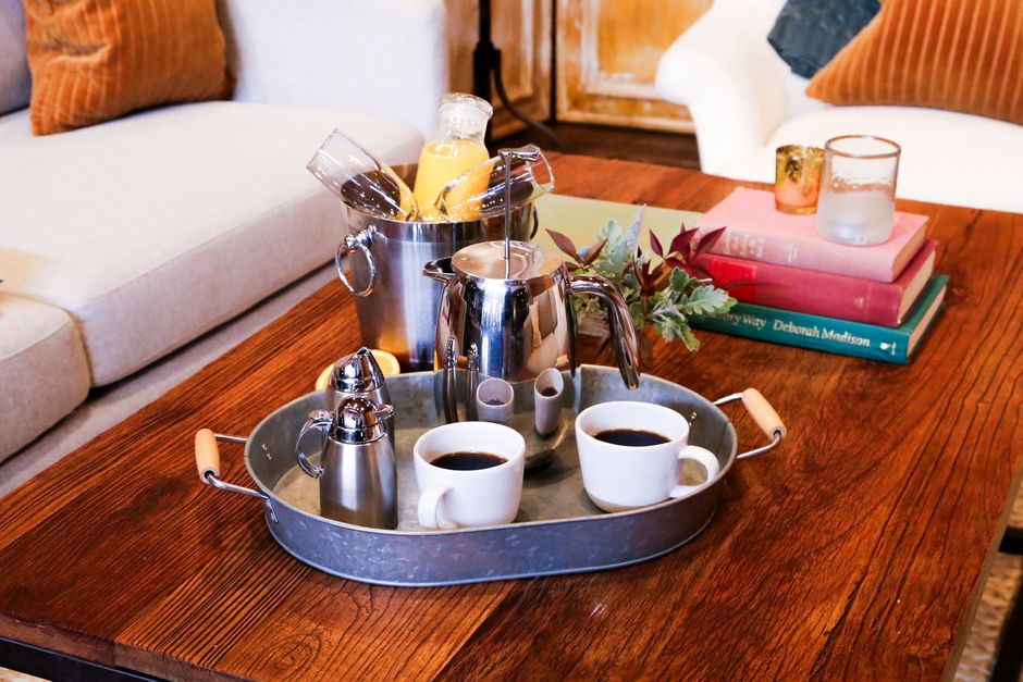 A tray with two cups of coffee and a bucket of champagne on a wooden table.