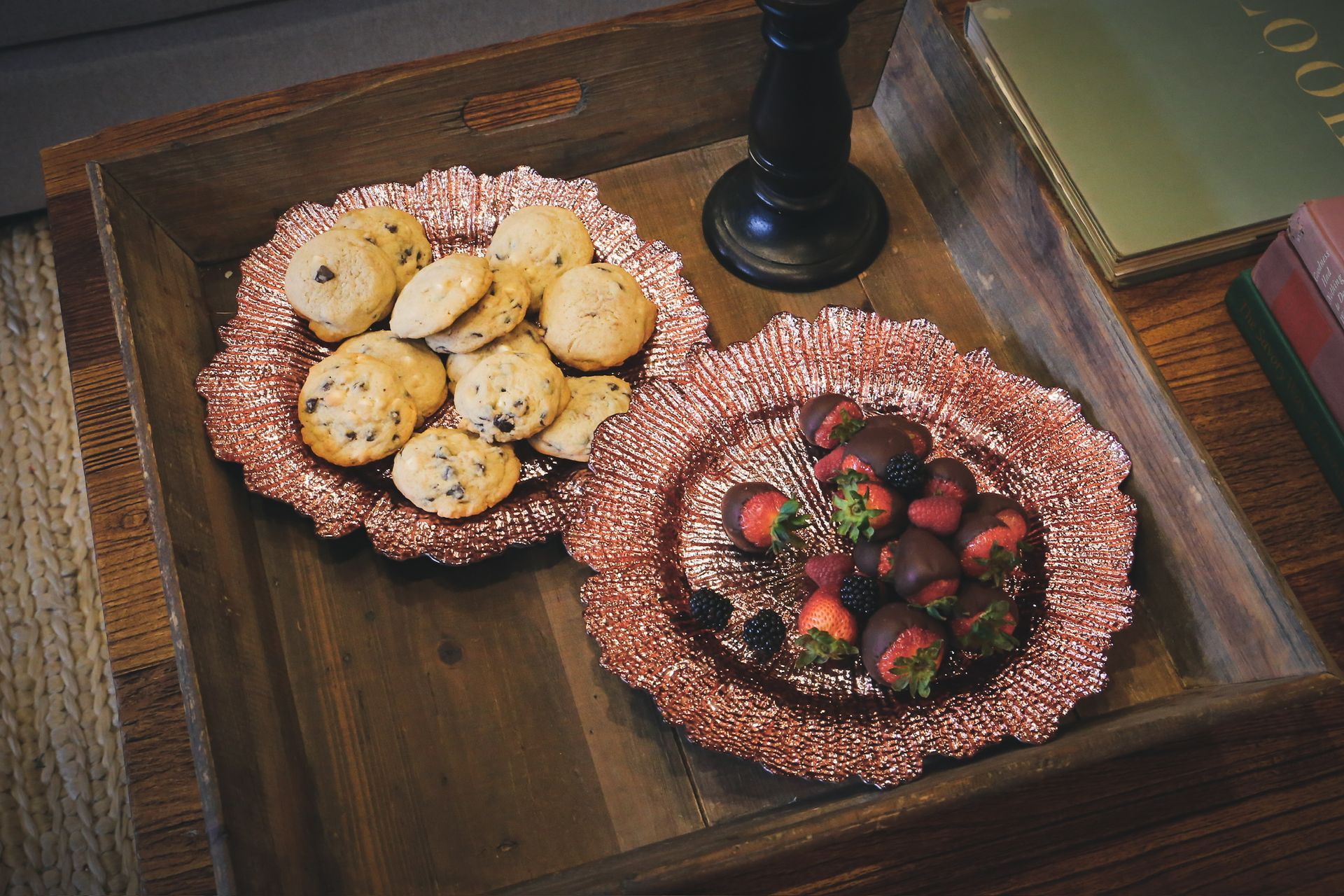 Two plates of cookies and strawberries on a wooden tray on a table.