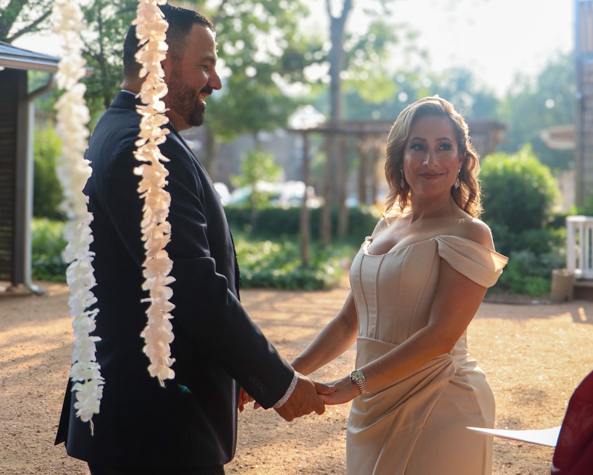 A bride and groom are holding hands during their wedding ceremony.