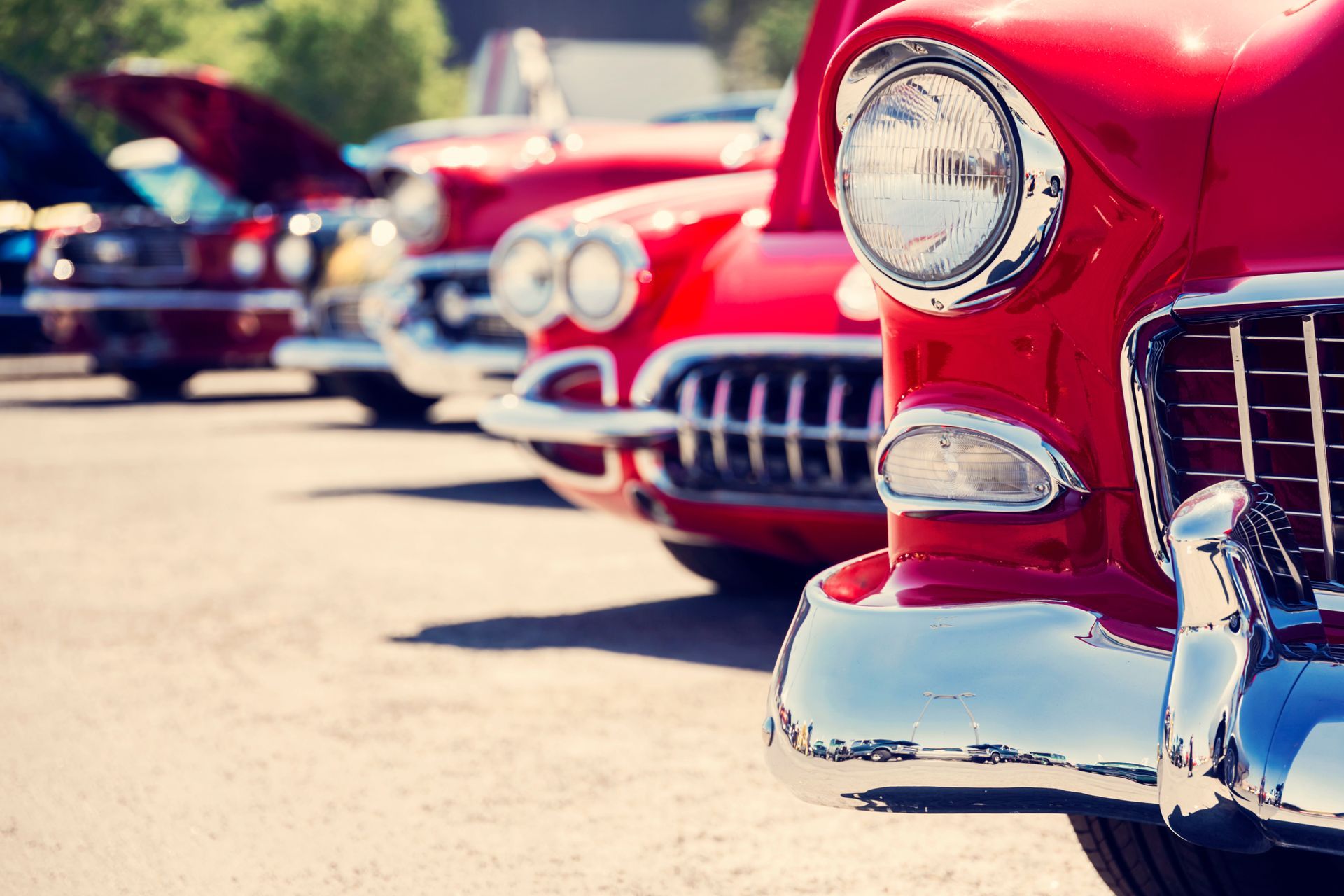 Classic red cars on display at an outdoor car show.