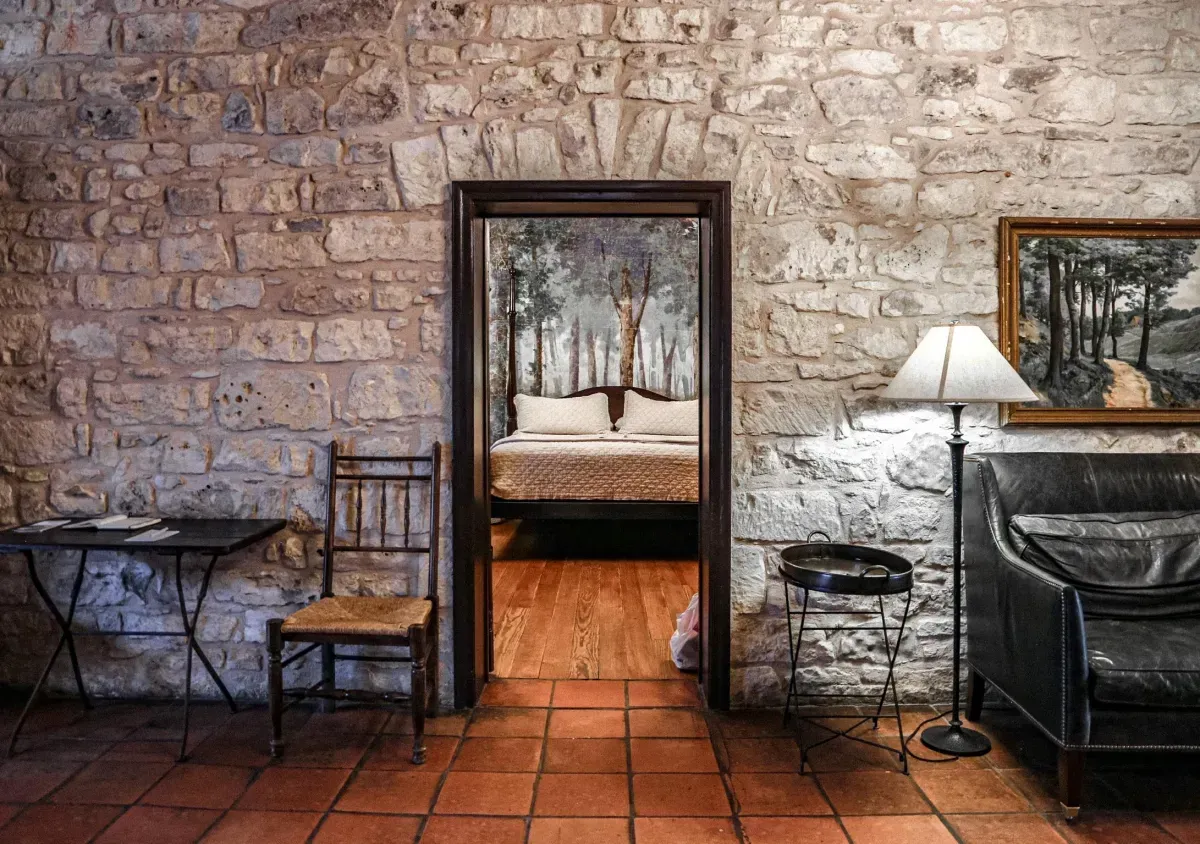 A living room with a brick wall and a doorway leading to a bedroom.