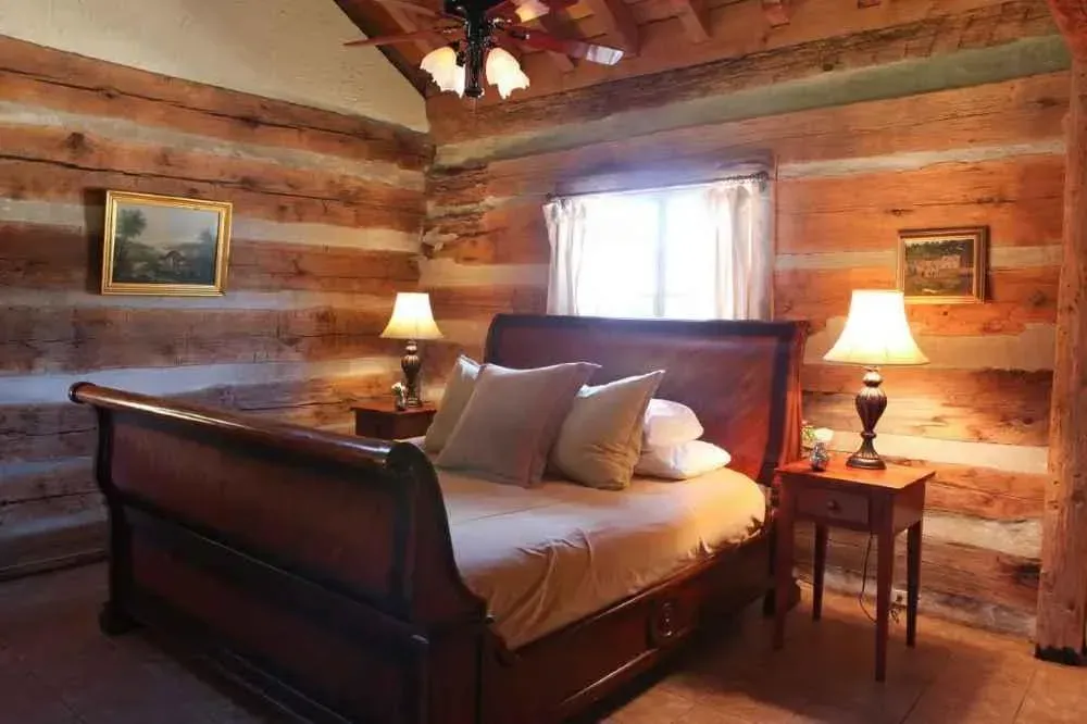 A bedroom in a log cabin with a king size bed and two lamps