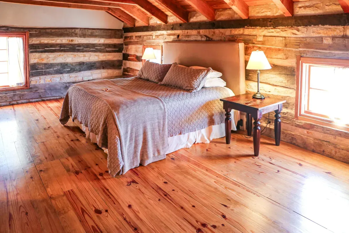 A bedroom in a log cabin with hardwood floors and a bed.