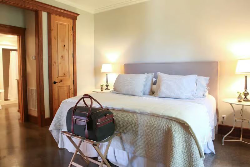 A bedroom with a large bed and a bag on a stand.