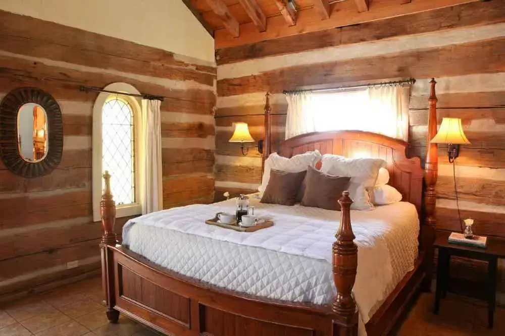 A bedroom in a log cabin with a bed and a window
