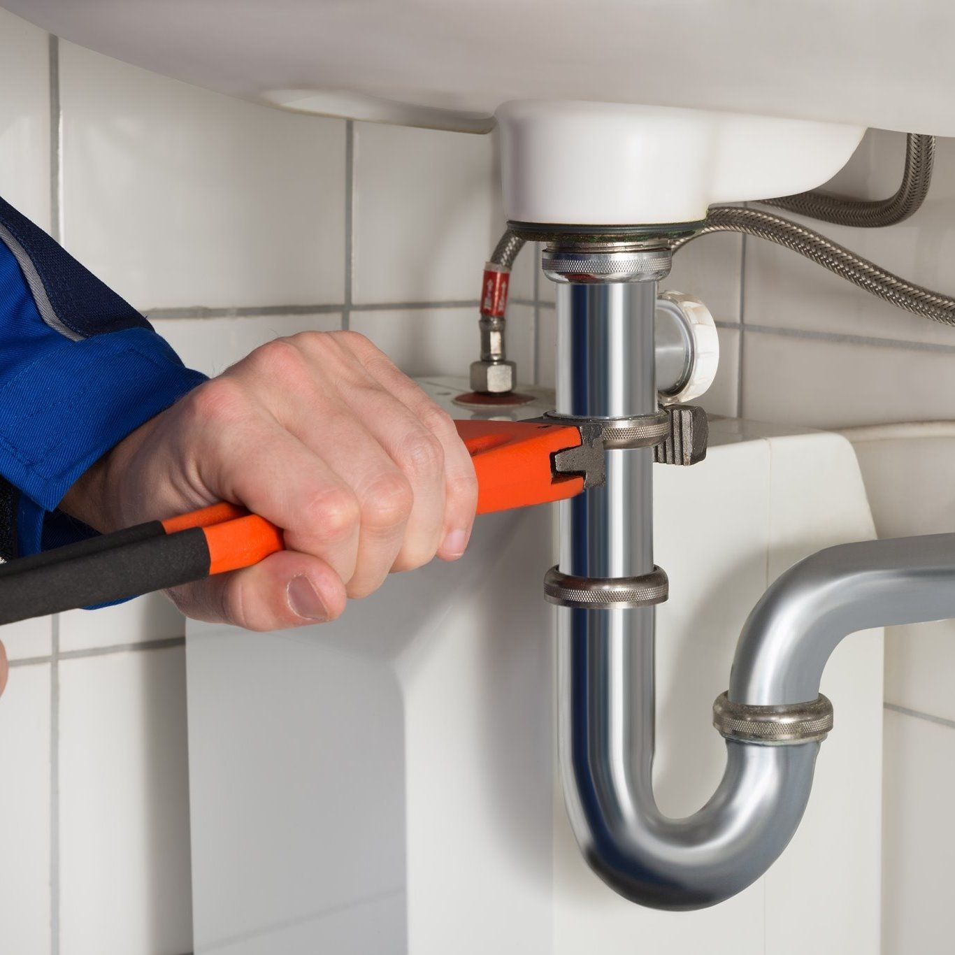 a plumber is fixing a sink with a wrench