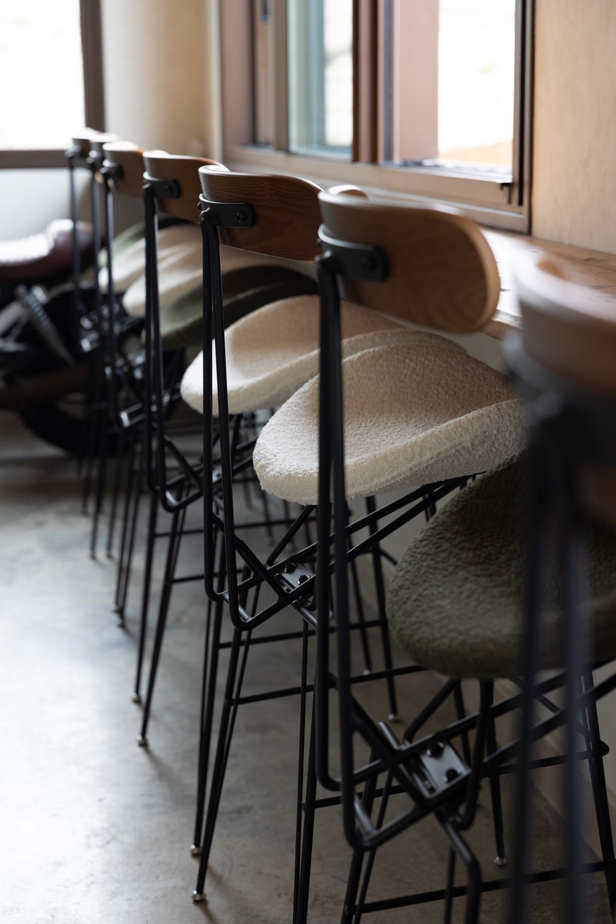 Sillas de madera alineadas junto a una ventana en una cafetería o aula tranquila.