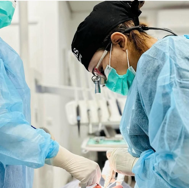 Chirurgen in blauwe jassen en maskers voeren een ingreep uit in een operatiekamer.