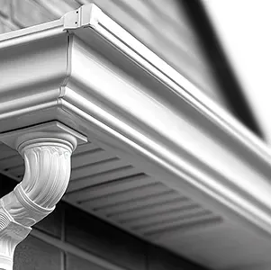 Close-up of a house gutter and ornate white downspout under the roof eaves.