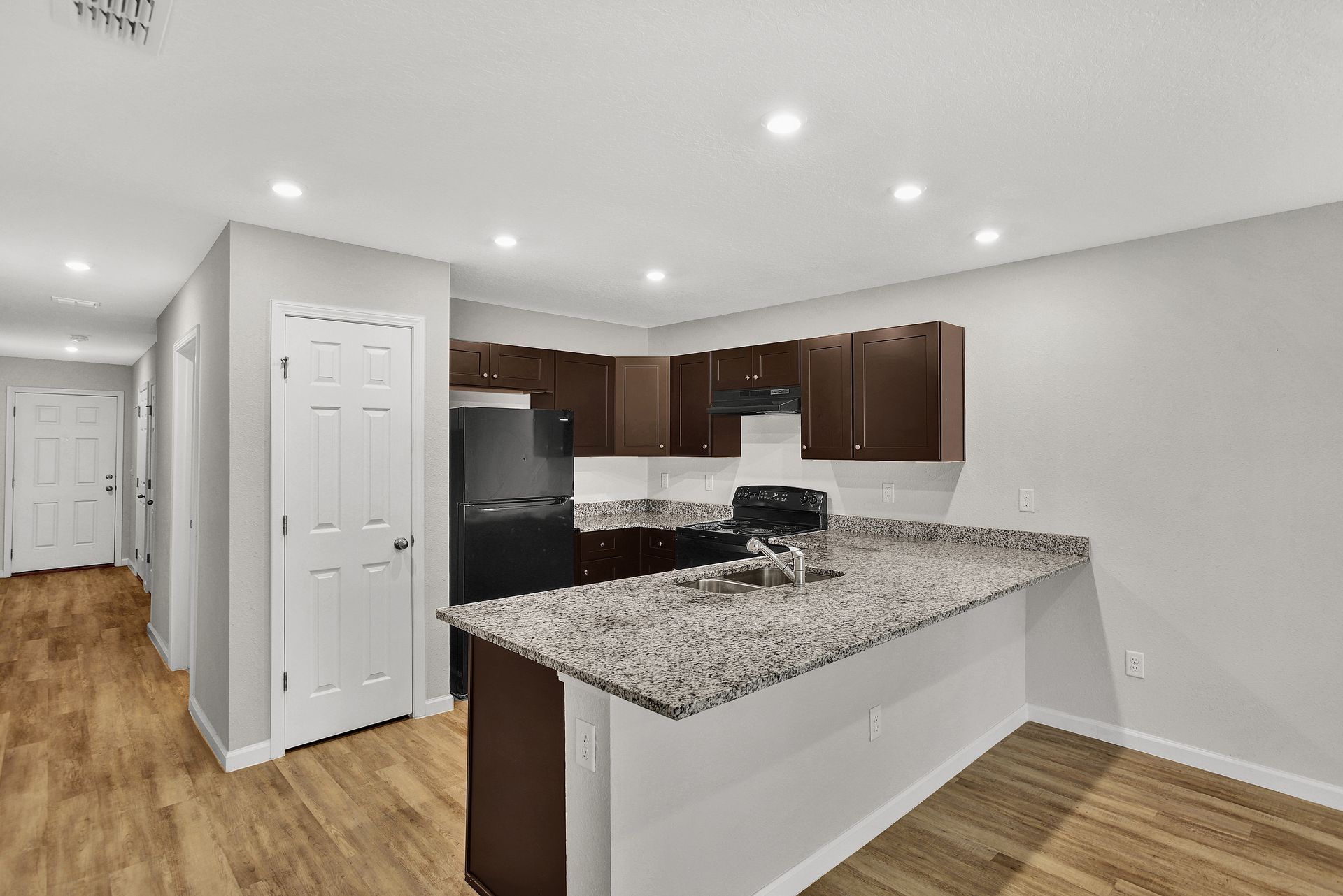 Kitchen with dark brown cabinets, granite countertops, and breakfast bar.