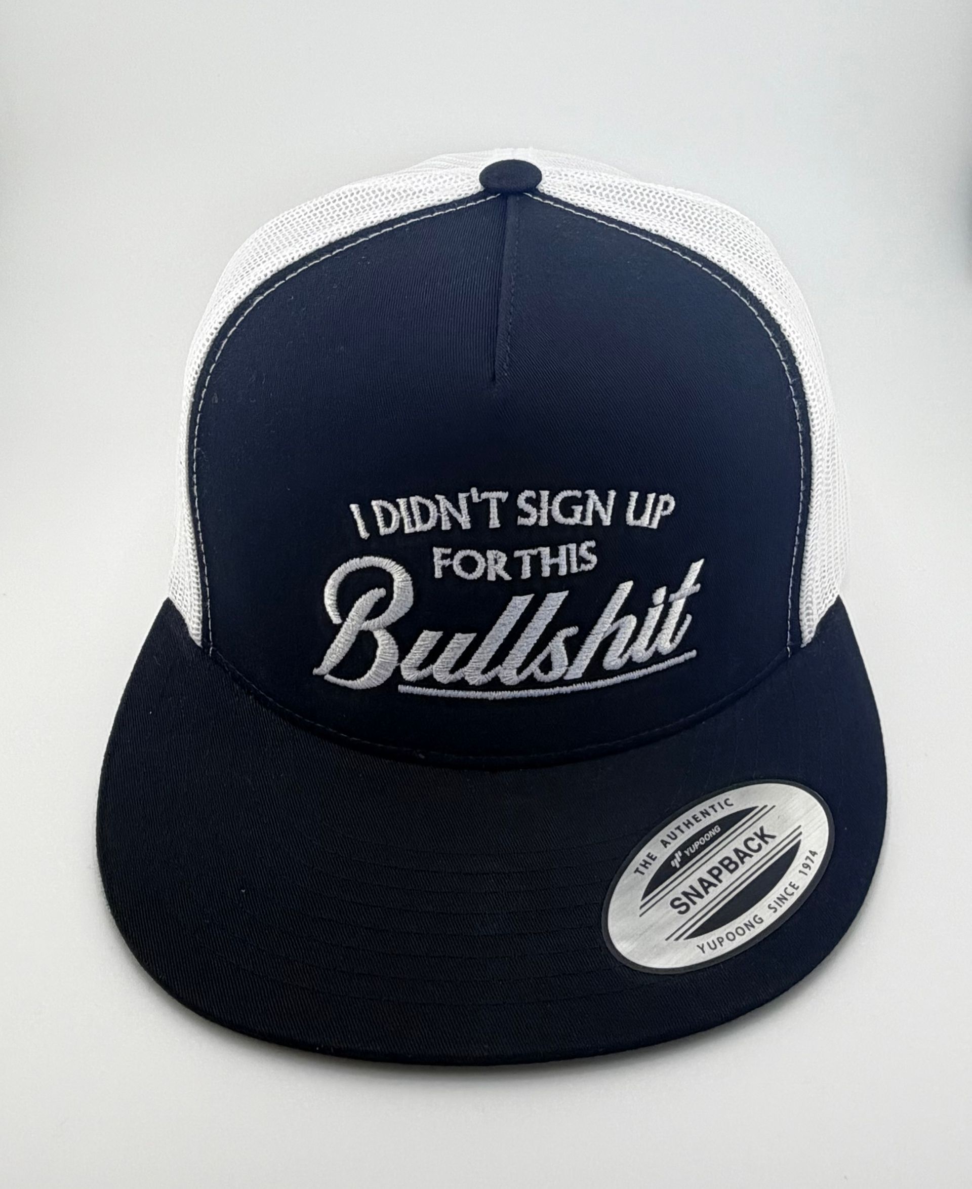A navy blue trucker hat with a white mesh back, featuring the embroidered text 