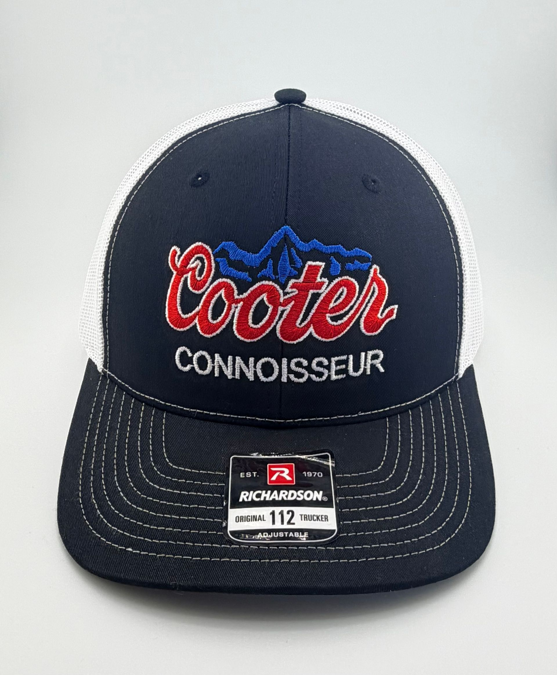 A navy and white Richardson 112 trucker hat featuring a red, white, and blue 