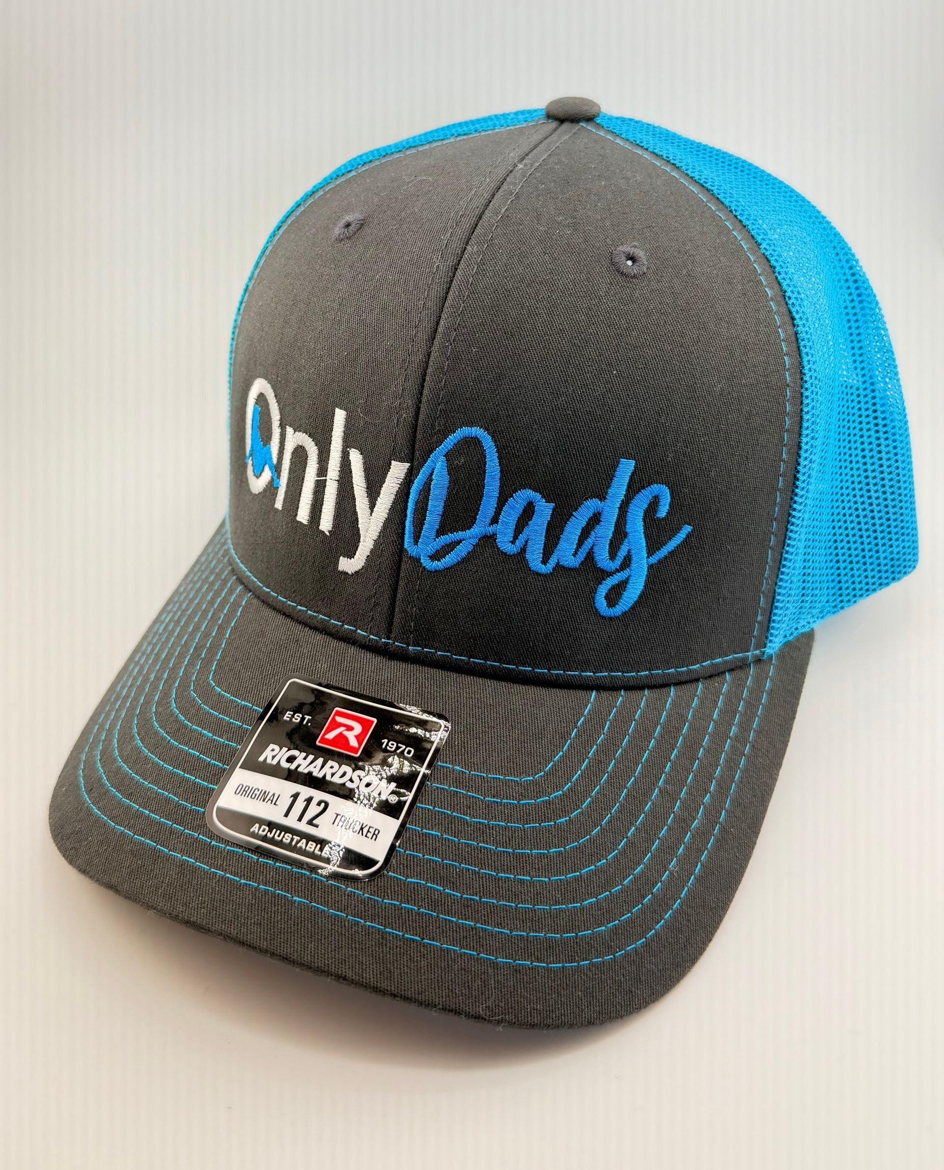 A grey trucker cap with a bright blue mesh back, featuring the white and blue embroidered text 