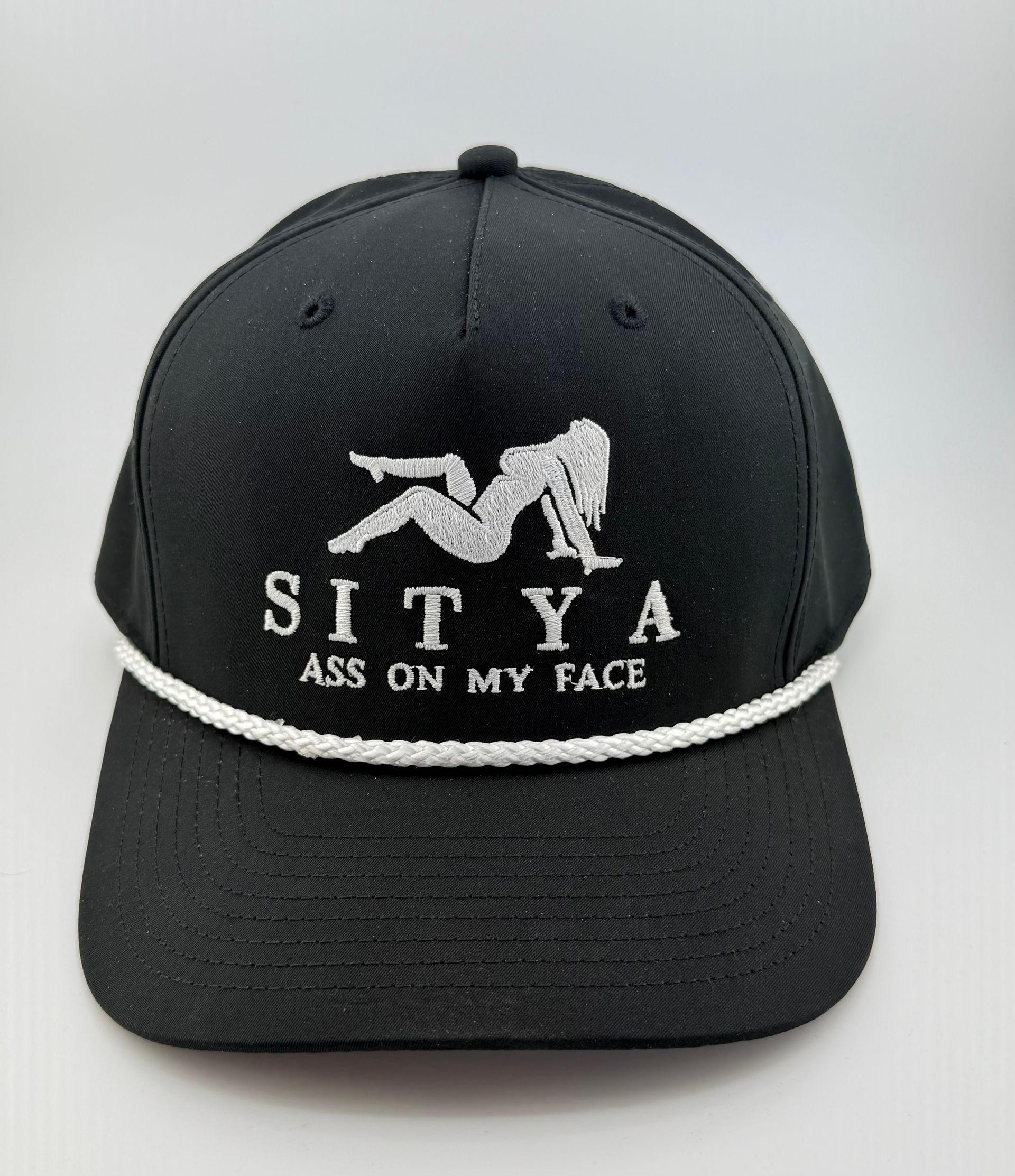 Black baseball cap with a white rope trim, featuring an embroidered silhouette figure and the text 