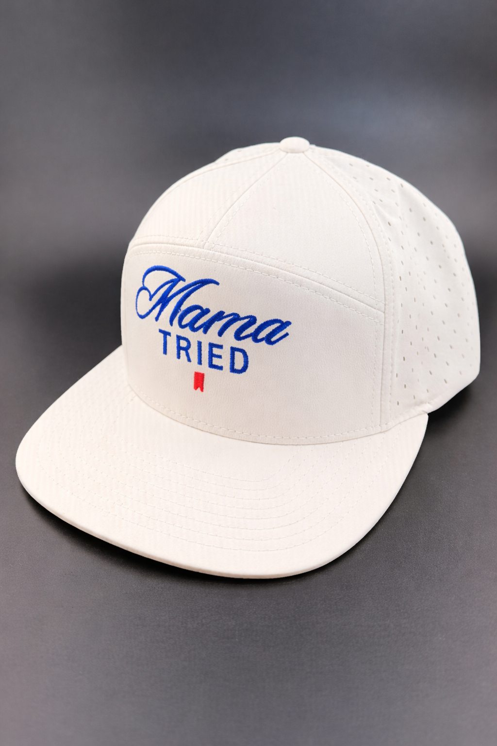 A cream-colored flat-brim baseball cap featuring the blue text 
