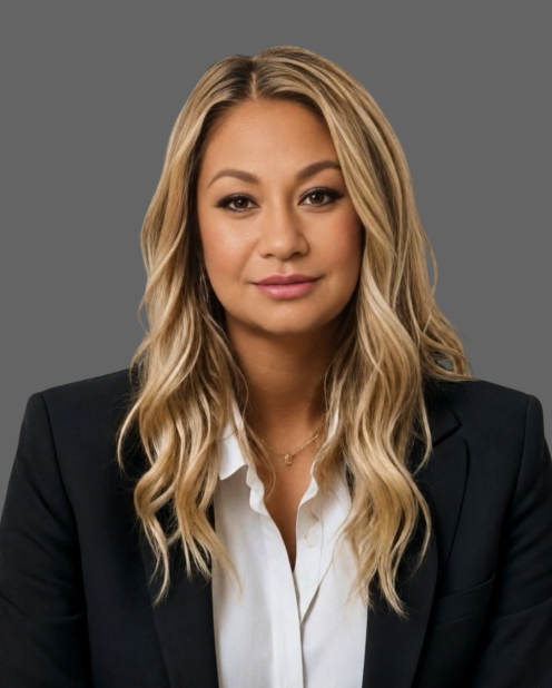 Portrait of a woman in a black blazer and white blouse against a gray background