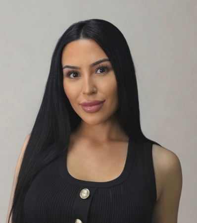 Portrait of a woman with long black hair wearing a black sleeveless top against a plain background