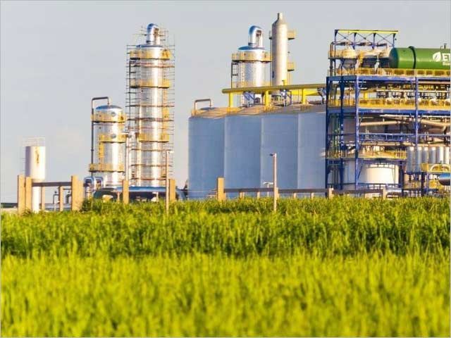 Uma grande planta industrial é cercada por um campo verdejante.