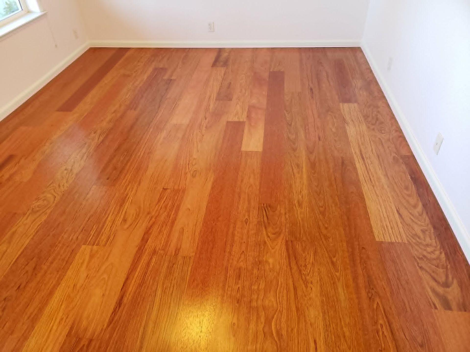 Empty room with glossy hardwood floor and white walls