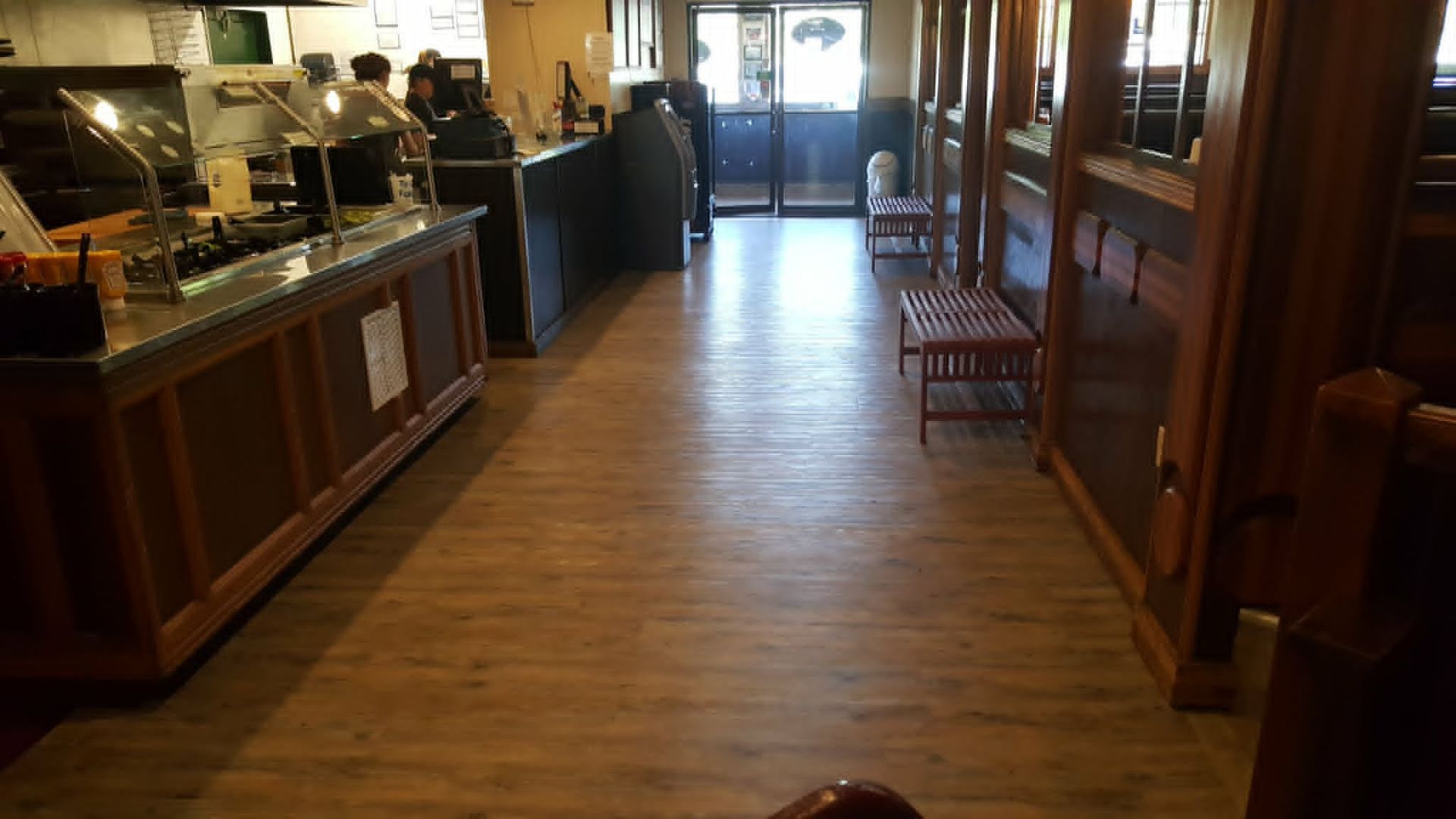 Wooden hallway in a restaurant with buffet counters, tables, and chairs